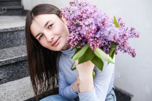 Preview: Smiling Young Woman with Lilac Bouquet on Steps