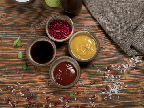 Preview: Different spices and sauces with a gray linen tablecloth on a wooden background, top view
