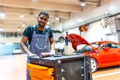 Preview: Car mechanic pushing tool trolley in auto repair shop