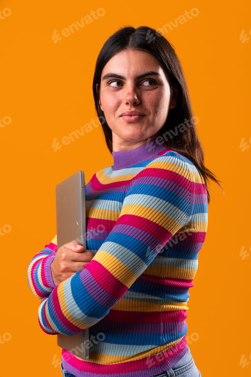 Preview: Young woman holding laptop and looking away on orange background