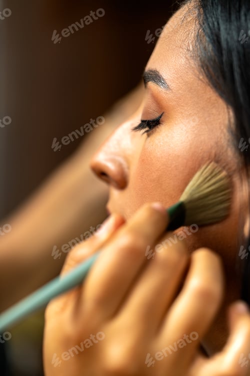 Preview: Professional hand applying makeup on woman's cheek