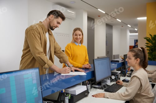 Preview: Man and woman couple signing document at modern clinic reception desk