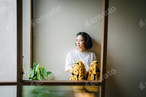 Preview: Thoughtful girl sitting on chair looking at window, sad depressed teenager spending time alone.
