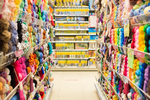 Preview: Shelves with colorful yarn balls at knitting store. Shop Needlework, counters with colored yarn.
