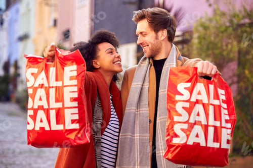 Preview: Multi Cultural Couple Sale Shopping In City Carrying Bags In Fall Or Winter