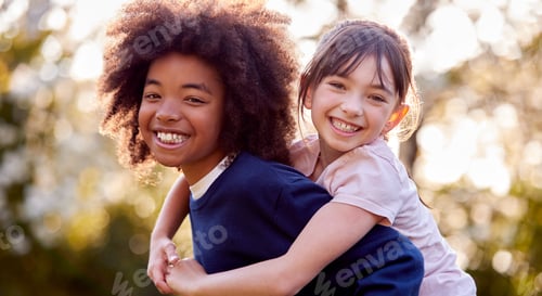 Preview: Portrait Of Smiling Boy Giving Girl Piggyback Outdoors In Garden
