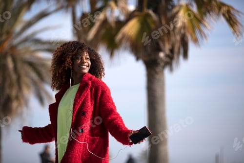 Preview: woman jumping and dancing while listening music and smiling outside