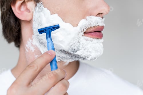 Preview: cropped shot of man with razor in hand and shaving foam on face on grey backdrop