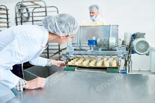 Preview: Factory worker pulling tray with pastry from confectionery machine