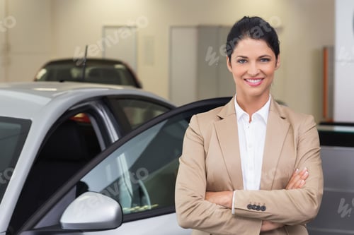 Preview: Female professional in blazer standing beside silver sedan with open door in showroom, copy space