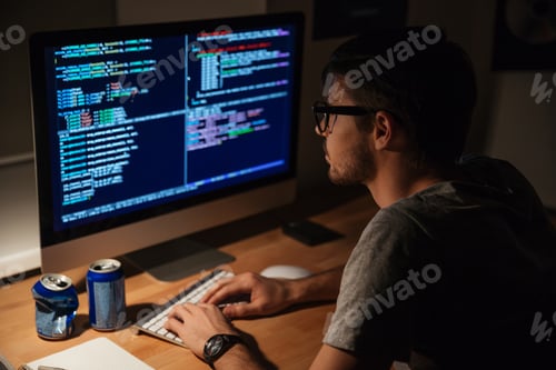 Preview: Thoughtful Young Programmer Coding On Computer In The Evening At Home