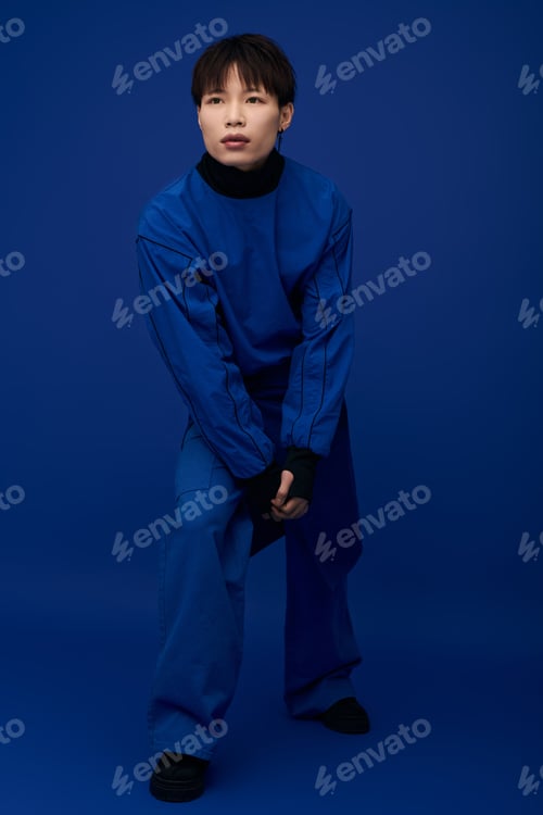 Preview: Young handsome asian man poses confidently in striking blue attire against a vibrant backdrop