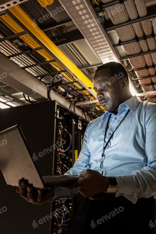 Preview: Black man technician doing diagnostic tests on computer servers in server farm.