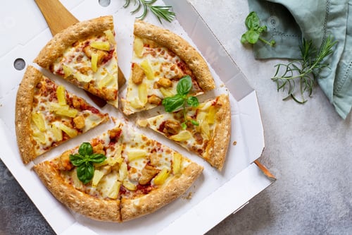 Preview: Pizza Hawaiian in a cardboard box on a light stone tabletop, food delivery.