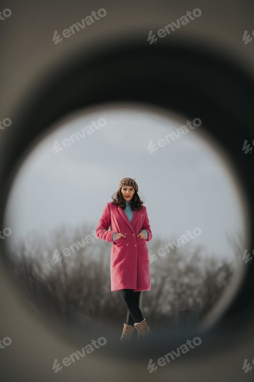 Preview: Beautiful Caucasian woman in a winter coat and bonnet posing on the snow seen through hole