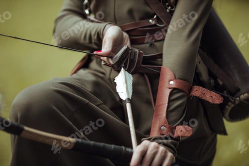 Preview: Close-up. Arrows and bow in female hands. Archery man in medieval costume.