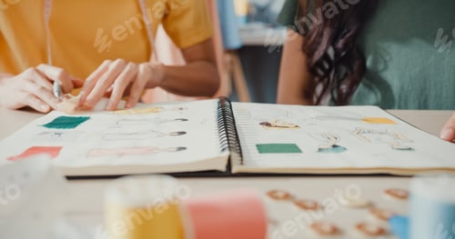 Preview: Asia lady designer teamwork meeting sketch book work on new collection share idea in shop.