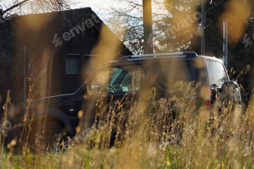 Preview: SUV is parked in a grassy area, viewed from the side.