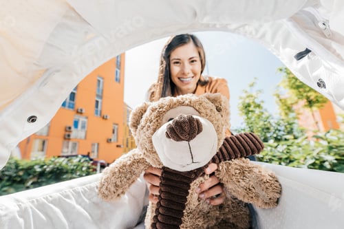Preview: smiling mother holding teddy bear in baby stroller