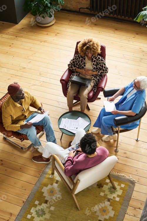 Preview: High angle of four intercultural economists having discussion at meeting