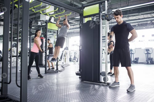 Preview: Young adult using exercise machine at gym