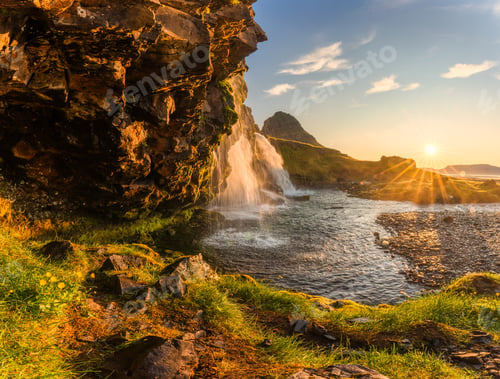 Preview: Sunrise over volcanic Kirkjufell mountain with waterfall flowing in summer at Iceland