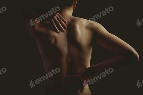 Preview: Nude woman with a back injury on black background