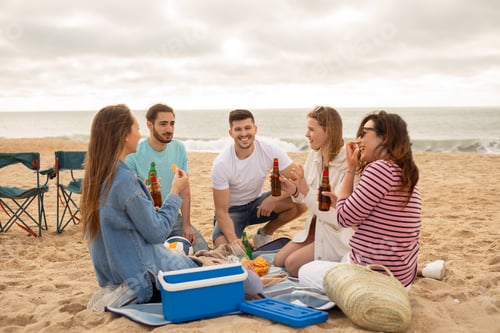 Preview: Friends enjoying a beach picnic with snacks and drinks during sunset