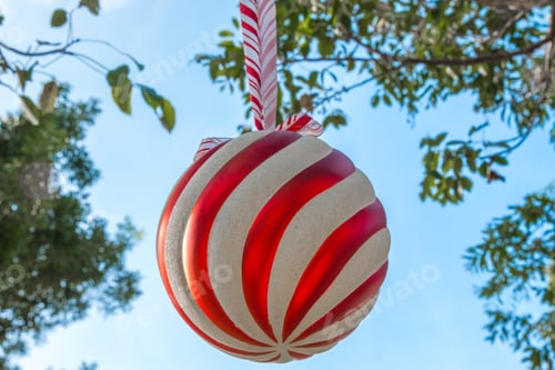 Preview: A big Christmas ball ornament hanging on a tree with blue sky