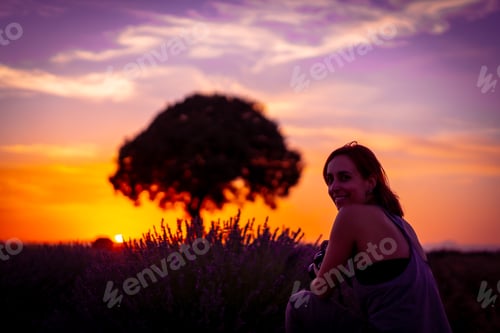Preview: woman photographs at sunset in a lavender field looking at the camera, Brihuega. Guadalajara, Spain.