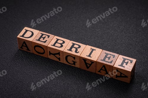 Preview: The inscription debrief in wooden cubes on a dark concrete background