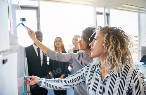 Preview: Diverse team of coworkers brainstorming together on an office whiteboard