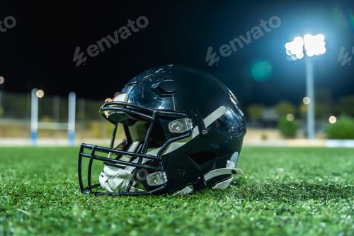 Preview: American football helmet lying on field at night