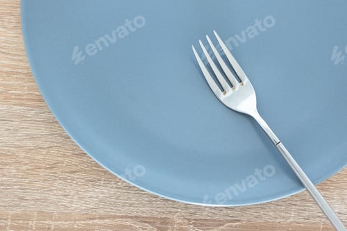 Preview: Close-up empty gray plate and silver fork on wooden table