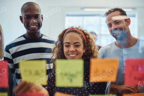 Preview: Smiling designers brainstorming together with sticky notes in an office