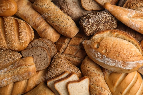 Preview: Different kinds of fresh bread as background, top view