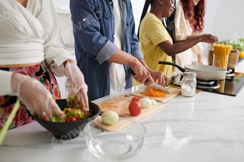Preview: Cropped shot of young intercultural friends in casualwear cooking food