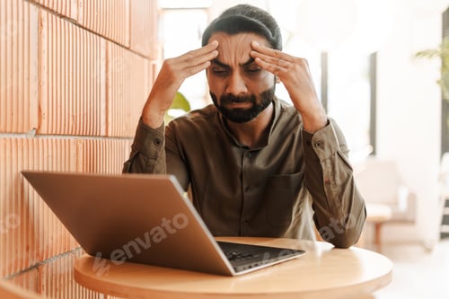 Preview: Stressed Indian businessman using laptop working, headache, something wrong, failed business