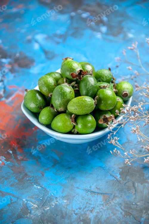 Preview: Vertical view of fresh natural delicious green feijoas in a white plate on blue background