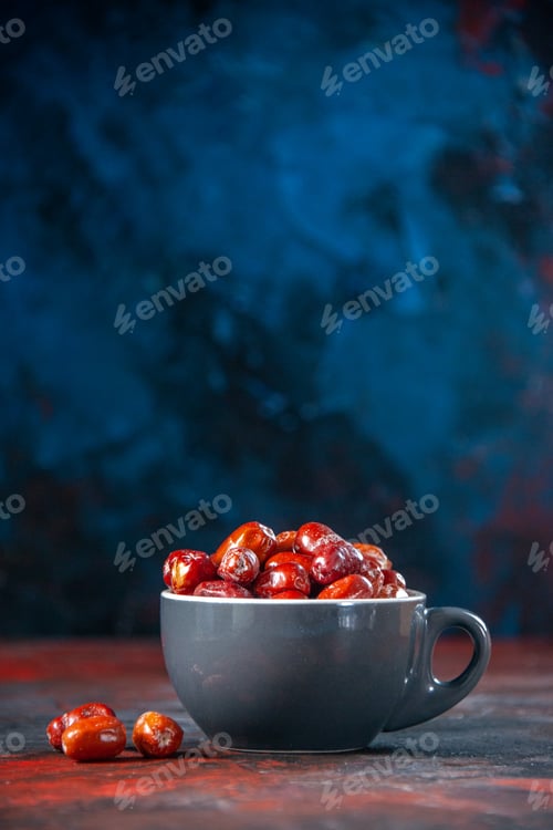 Preview: Vertical view of fresh raw silverberry fruits inside and outside of a gray cup on mix colors