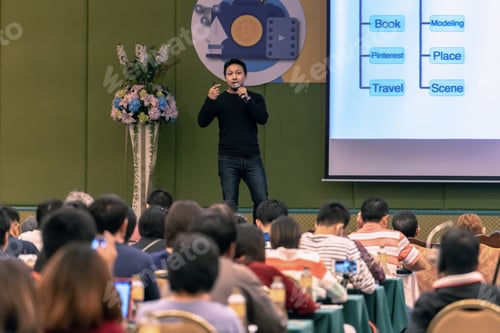 Preview: Asian Speaker with casual suit on the stage present the screen in the conference hall