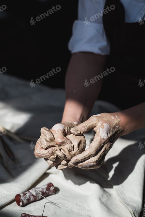 Preview: Close-up of a woman potter sculpts a brown clay pot on the background of a wooden table in the