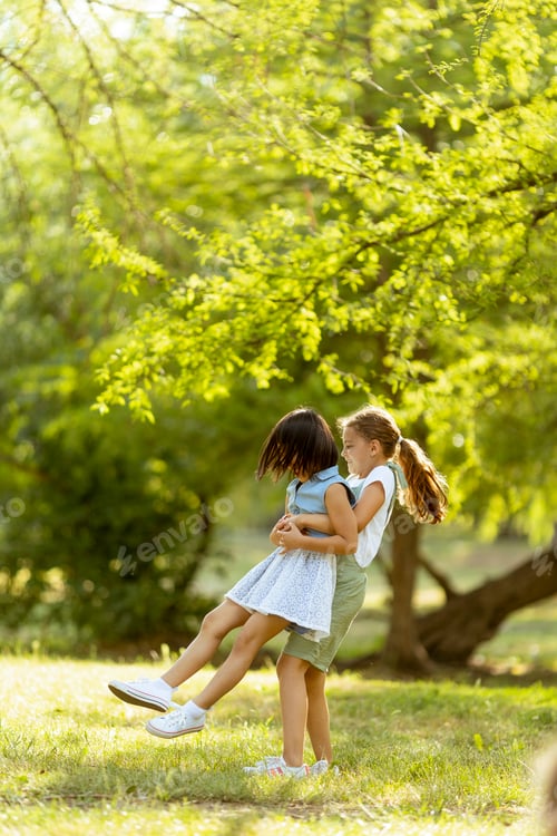 Preview: Cute asian and caucasian girl having fun in the park