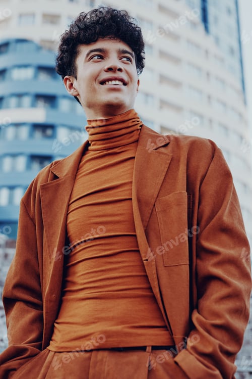 Preview: A young man in an orange outfit standing confidently against a modern city backdrop