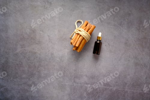 Preview: cinnamon essential oil in a container on a black background top view