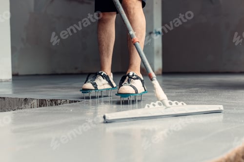 Preview: A construction worker apply grey epoxy resin in an industrial hall