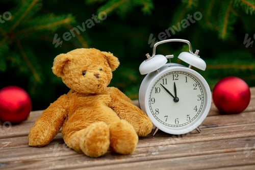 Preview: vintage alarm clock and teddy bear on wooden table with spruce branches on background