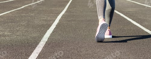 Preview: Crop image of female sporty legs and feet in running shoes at the stadium