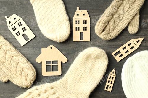 Preview: Wooden houses and knitted clothes on gray wooden table