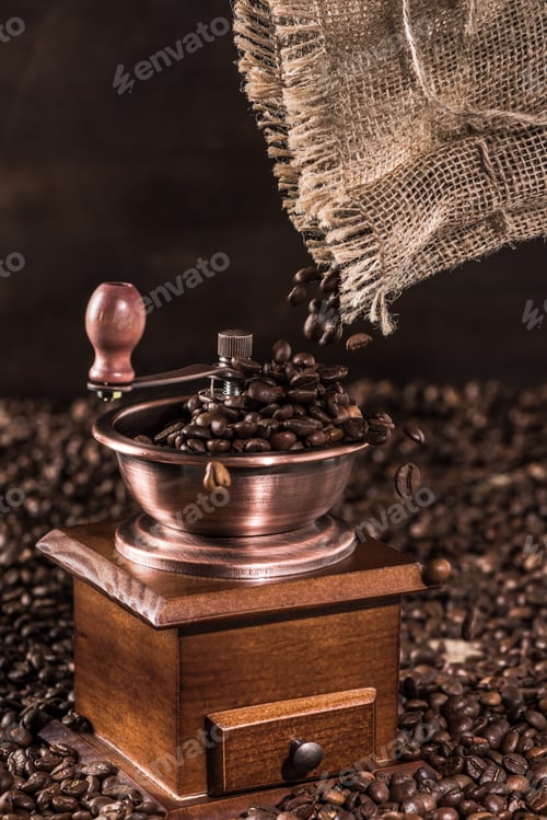 Preview: Close up view of coffee mill with aromatic coffee beans on brown